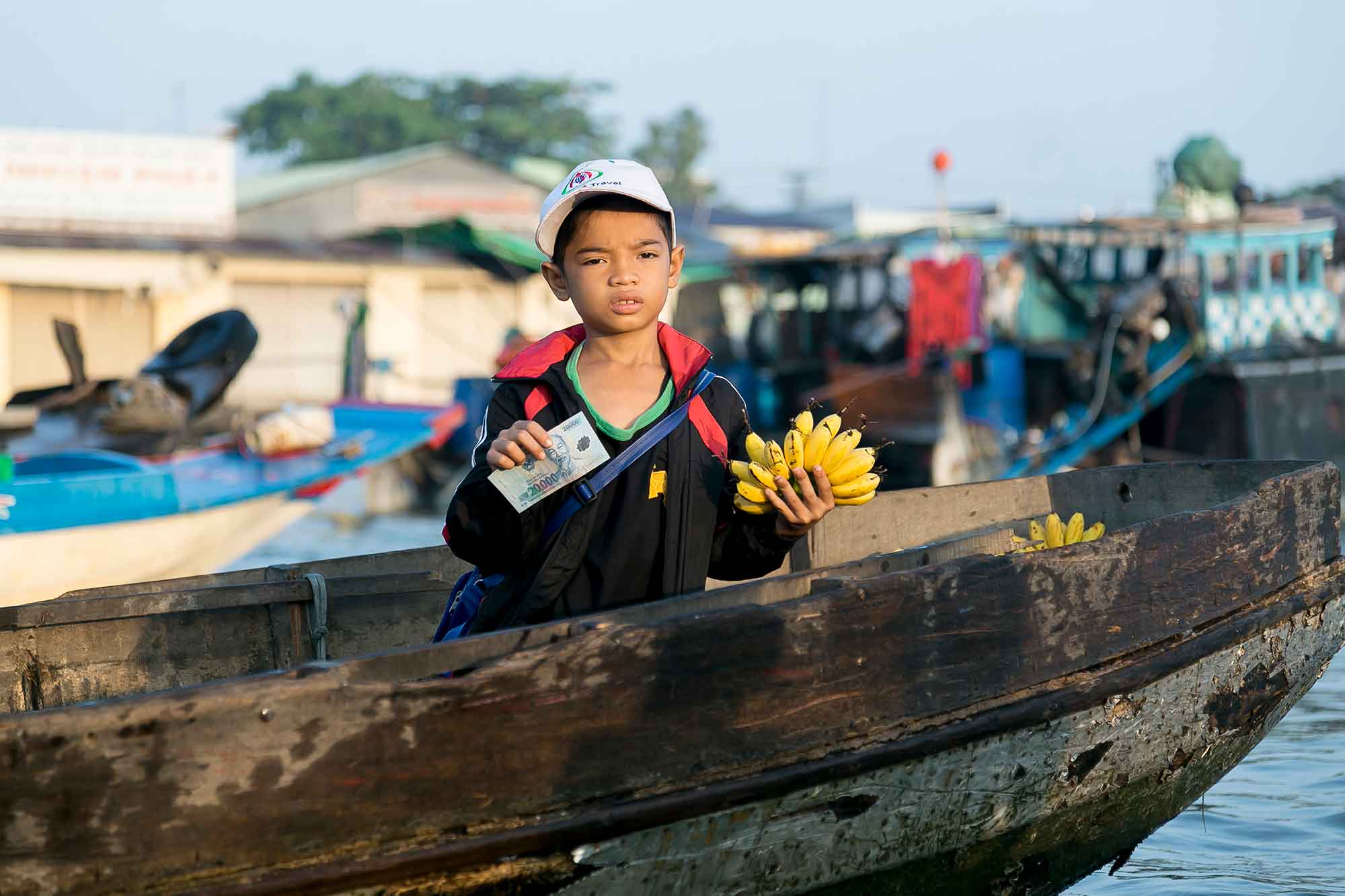 Vietnam-dreng sælger bananer på vandmarked